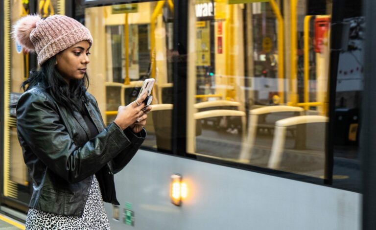 Female at tram station searching the internet on a phone