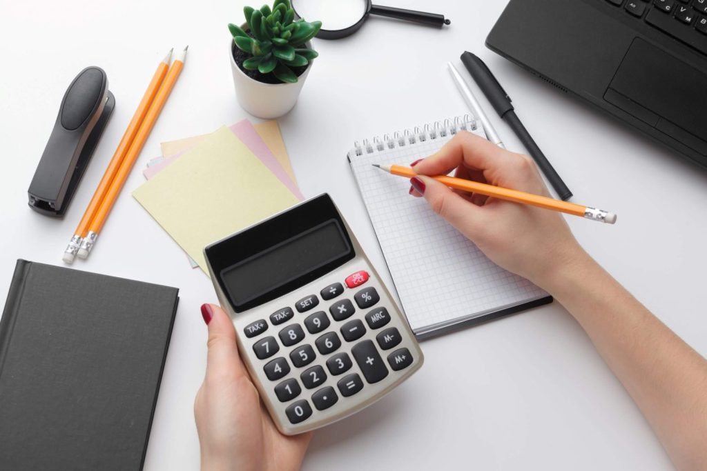 Calculating budget with calculator and notepad